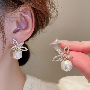 Detailed close-up of crystal bow earrings with white pearl drops and gold plating