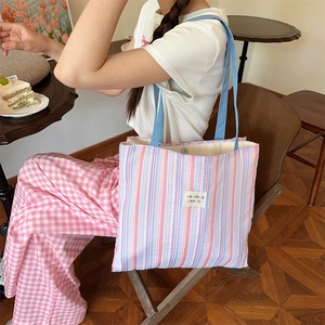 Dettaglio della trama a righe rosa e blu della borsa tote con etichetta logo