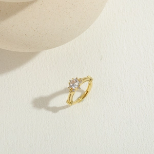 Détail d'une bague plaquée or 14 carats avec zircon central rond et accents pavés