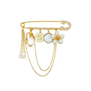 Elegant gold flower brooch with pearls, crystals and perfume bottle charms on white background