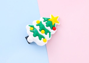 Detail of Christmas tree hair clip with festive resin ornaments on a blue and pink background