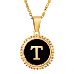 Detail view of gold titanium steel pendant featuring a black enamel letter T charm