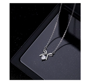 Detail of silver S925 bow pendant necklace featuring a sparkling heart-shaped zircon