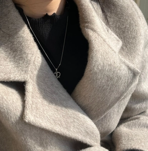 Close-up of a 925 sterling silver twisted heart necklace on a black turtleneck sweater