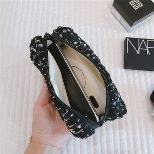 Detail of tweed makeup pouch with black zipper showing storage of phone and mirror