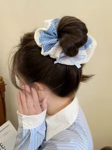 Detail of blue plaid hair scrunchie with white lace and bow, worn by a model