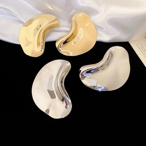 Polished metallic irregular abstract earrings in gold and silver finishes on velvet