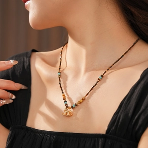 Close-up of vintage tiger eye stone beaded necklace with gold animal pendant on model