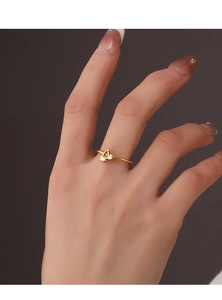 Detail of a minimalist gold coconut tree ring worn by a model on a dark background