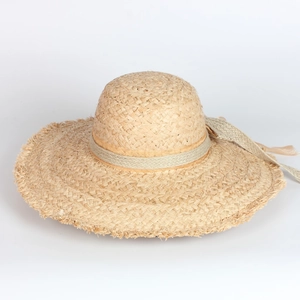 Close-up of woven raffia sun hat texture with green ribbon and fringe wide brim detail