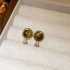 Detail view of brown tiger eye stone earrings with golden base on a jewelry tray
