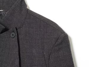 Detailed close-up of dark grey blazer shoulder seams and fine textile texture