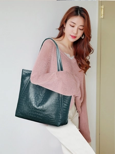 Detail shot of the deep green crocodile texture on a large capacity tote shoulder bag