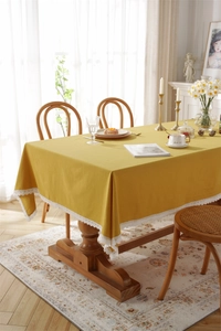 Macro detail of a yellow cotton tablecloth featuring elegant white lace embroidery edges