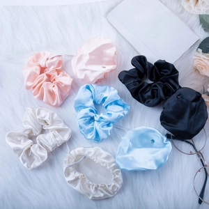 Silk scrunchies set in black, beige, blue and pink colors on a soft plush background