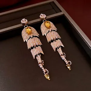 Boucles d'oreilles vintage dorées à glands avec gemmes jaunes et perles sur support brun