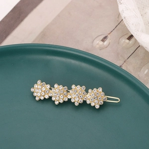 Close-up of golden hair clip with four rhinestone flowers on a vintage green plate