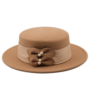 Détail du chapeau canotier en laine camel avec ruban satiné et nœuds ornés de perles