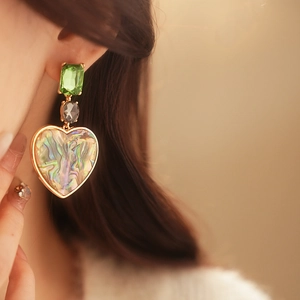 Detail of vintage heart earring with colorful abalone shell and green gemstone inlay
