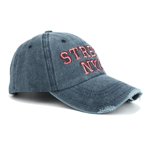 Detailed close-up of red NYC embroidery on washed denim vintage baseball cap with distressed brim