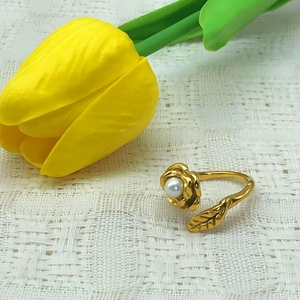 Elegant gold camellia open ring with a pearl on a white lace background with flowers