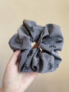 Dettaglio di un fermaglio per capelli grigio con fiocco in denim e stampa nera elegante