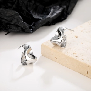 Macro view of silver geometric stud earrings with irregular abstract wave surface texture