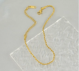 Detailed view of 18k gold plated twist chain anklet with lobster clasp on glass