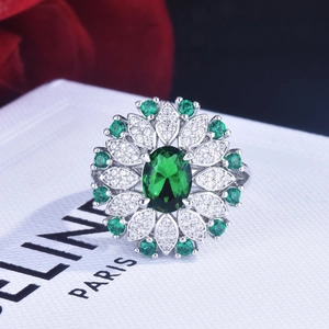 Detail shot of a flower-shaped ring with emerald green center stone and diamond accents