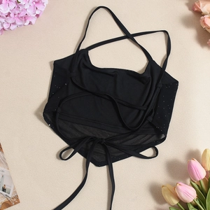Detail eines schwarzen Halter-Crop-Tops mit gekreuzter Rückenschnürung und Glitzereffekt