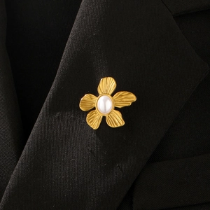 Detail of vintage gold flower brooch with white pearl on black suit jacket lapel