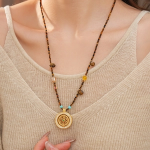 Detail view of tiger eye bead necklace with intricate hollow flower pendant on model