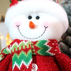 Close-up of plush Christmas snowman doll featuring knitted scarf and red sequin clothes