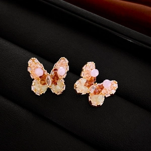 Macro detail of crystal butterfly earrings with champagne stones on black leather