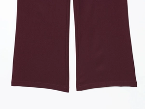 Macro shot of flared hemlines and fine stitching on deep red trousers set
