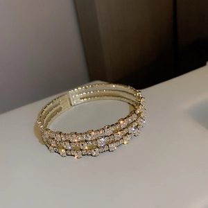 Detail of luxury triple-row diamond bracelet with gold finish and sparkling rhinestones