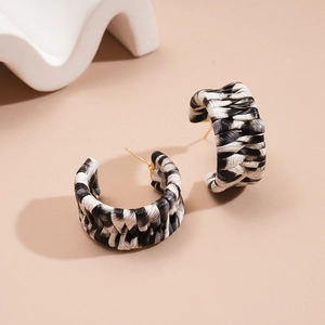 Detail view of C-shaped woven earrings with black and white grid texture and gold studs