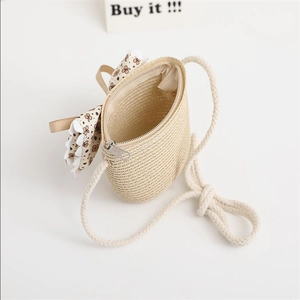 Detail of straw crossbody bag with floral bow, zipper closure and rope strap