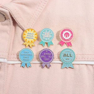 Detailed close-up of six creative metal award pins on pink denim jacket with funny quotes