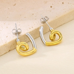 Detailed macro view of irregular spiral heart earrings in two-tone gold and silver finish