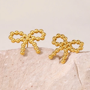 Boucles d'oreilles nœud dorées élégantes avec texture perlée sur pierre claire