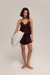 Lace-trimmed burgundy satin camisole and shorts sleepwear set on a model in a studio