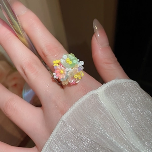 Dettaglio di un anello floreale fatto a mano con perle in resina colorate e fascia in metallo