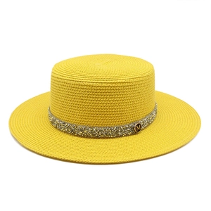 Detailed view of the yellow straw hat with a rhinestone band and gold M logo