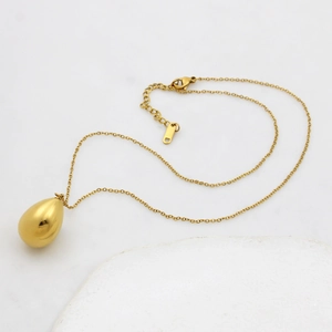Gold plated stainless steel water drop pendant necklace on white marble background