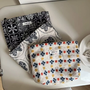 Three-piece set of embroidered canvas pouches with floral patterns and woven labels