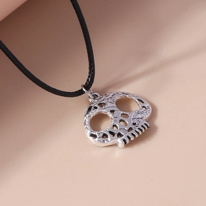 Close-up of a silver skeleton hand pendant with intricate textures on a black woven cord