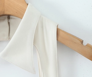 Detailed macro view of white cotton blend fabric texture and collar stitching on wooden hanger