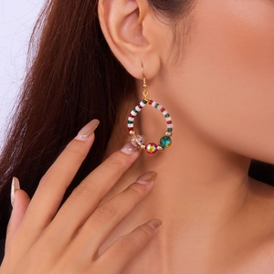 Close-up of elegant Christmas wreath earrings with colorful beads and clear crystals