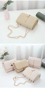 Detail of woven straw chain bag featuring natural texture and gold V-shaped metal hardware